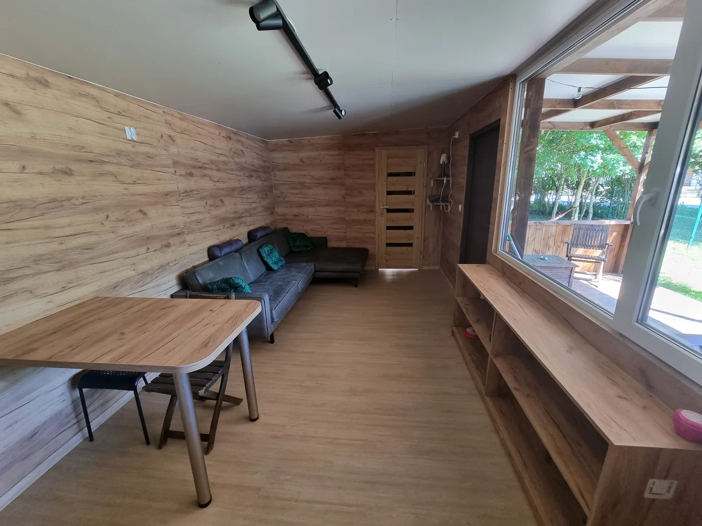 Salon domku MaziHouse z drewnianym wykończeniem i panoramicznym oknem